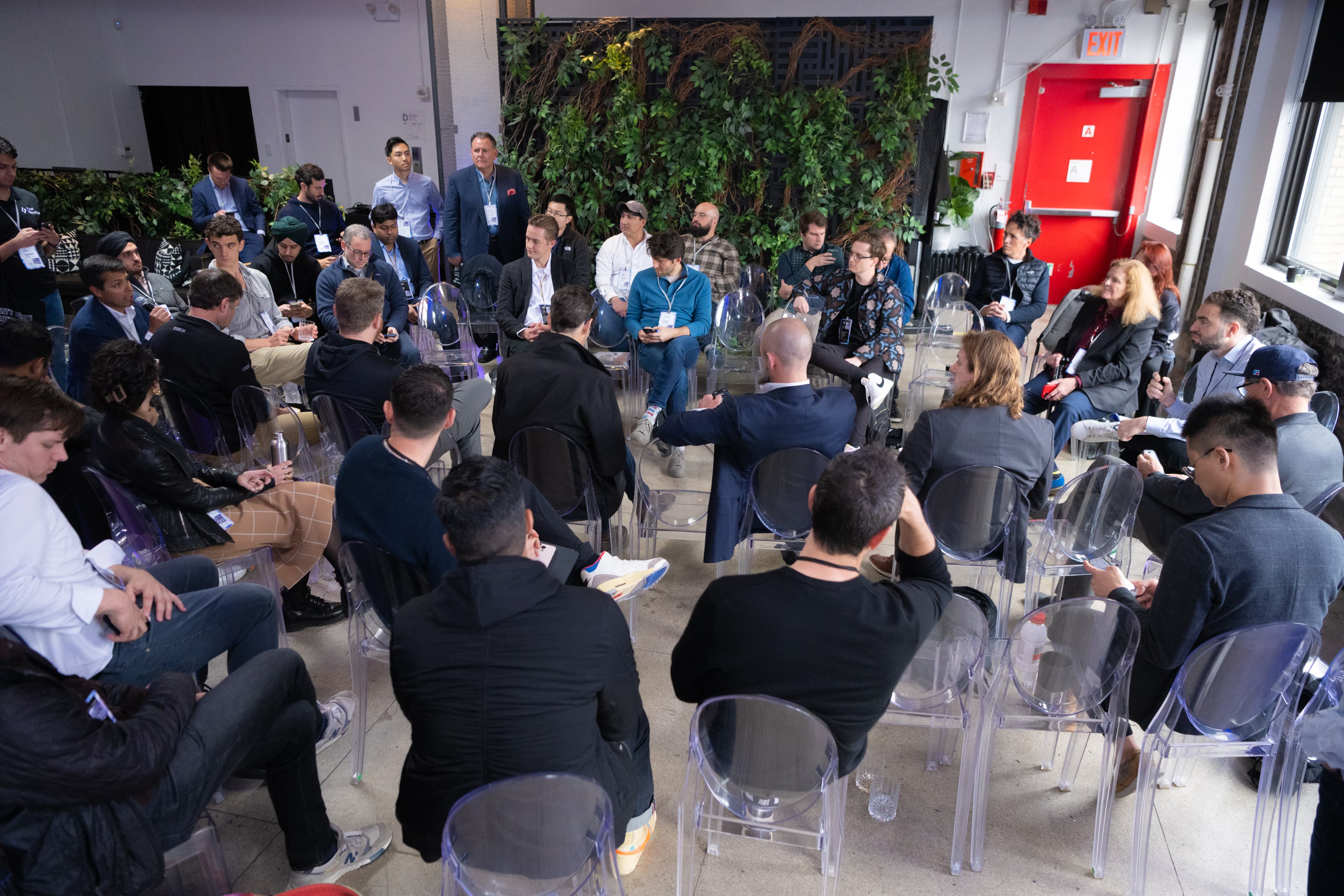 A roundtable discussion among attendees seated in clear chairs at Dirty Jobs Summit